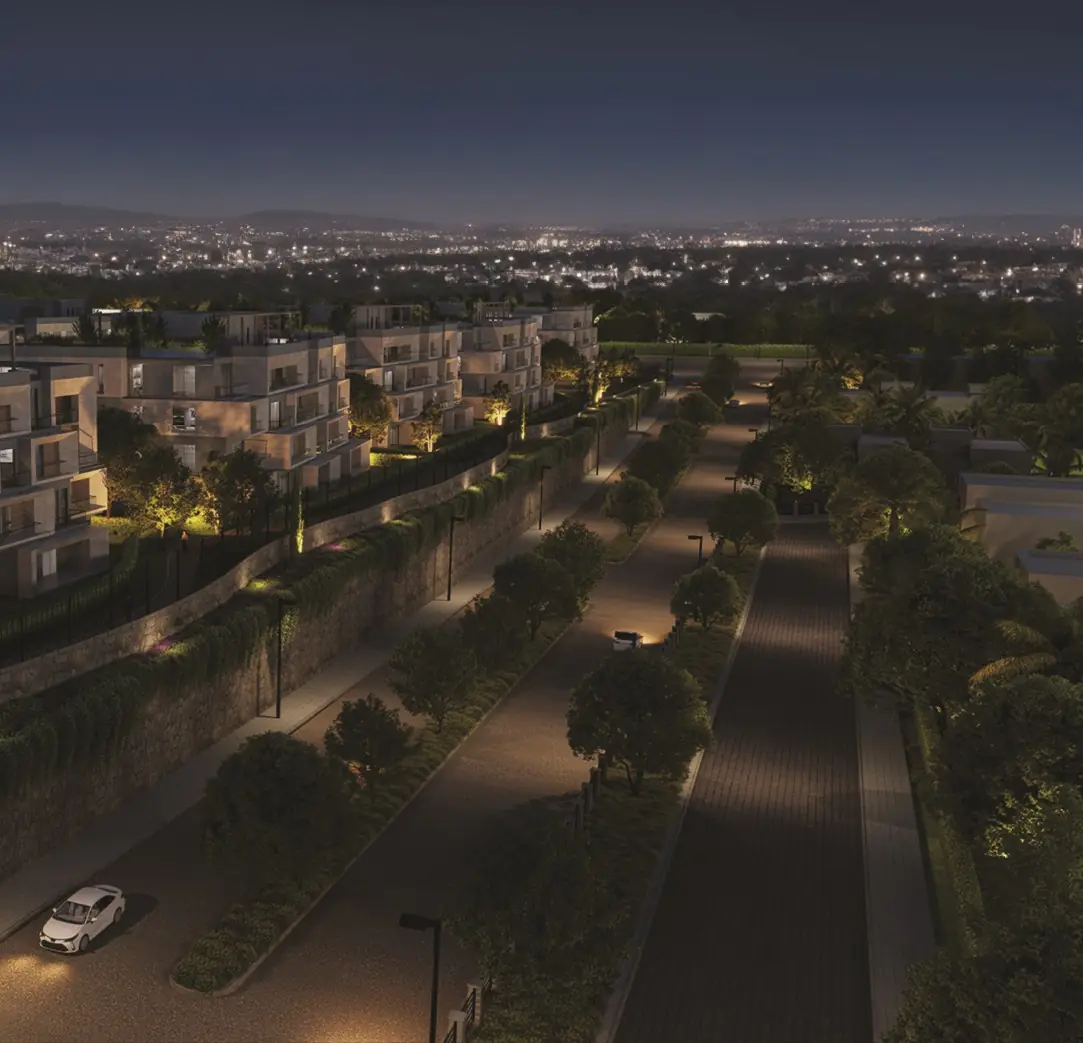 31 West – Night view of a lit boulevard below terraced apartments, city lights beyond