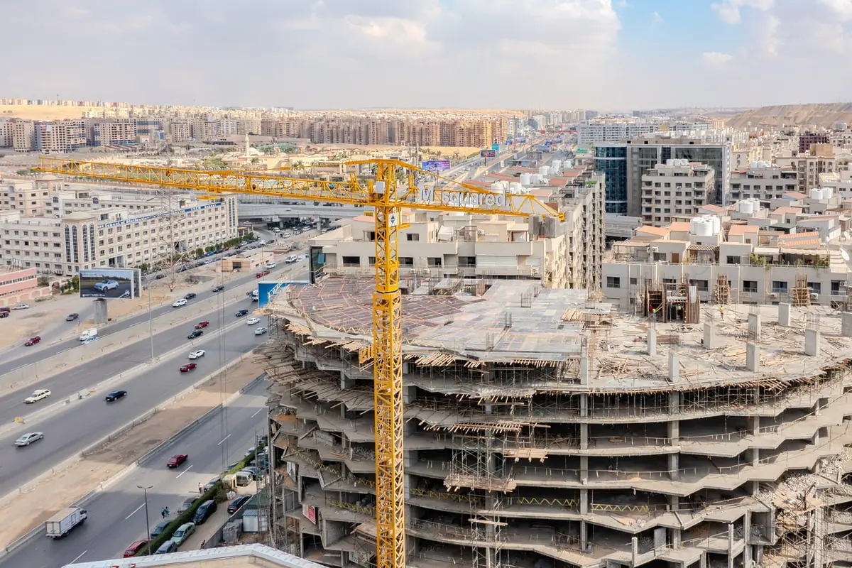41 Business District – Baustelle mit Turmdrehkran und Betonrohbau neben einer stark befahrenen Schnellstraße