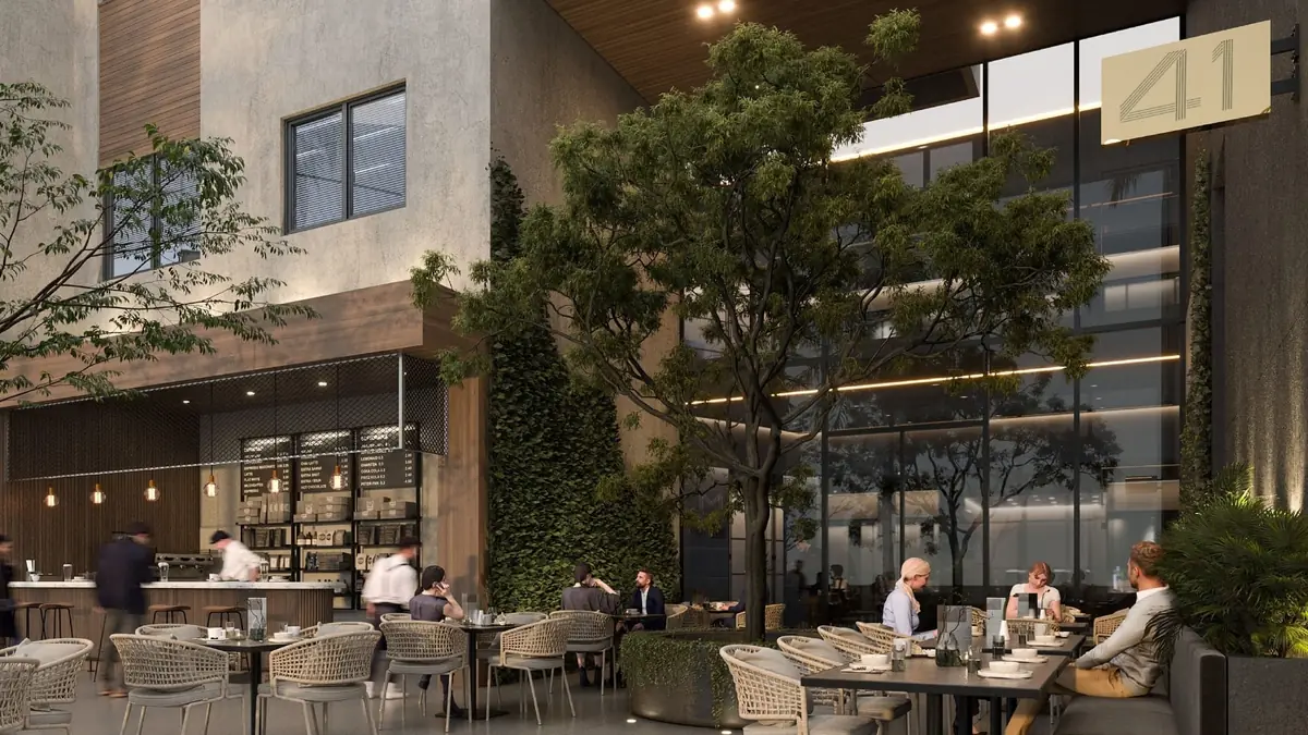 41 Business District – Café-Terrasse im Freien mit Gästen unter Bäumen neben dem verglasten Eingang