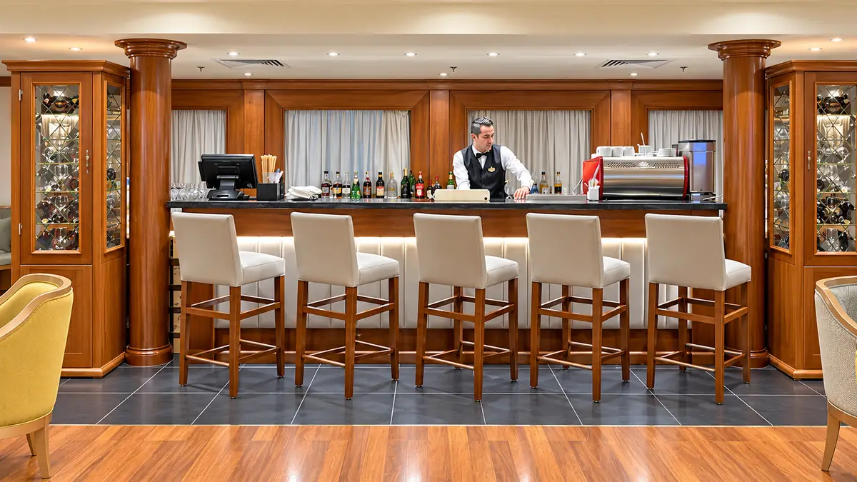 Amwaj Boat Renovation – Polished wood lounge bar with a row of cream bar stools
