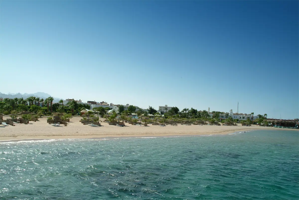 Lotus Bay Resort Renovation – View from the water to the sandy beach and the resort's low buildings