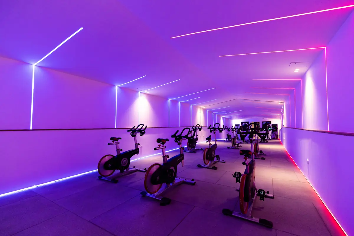 Move – Green Heights Sports Complex – Spinning studio with rows of bikes under pink and violet neon lines