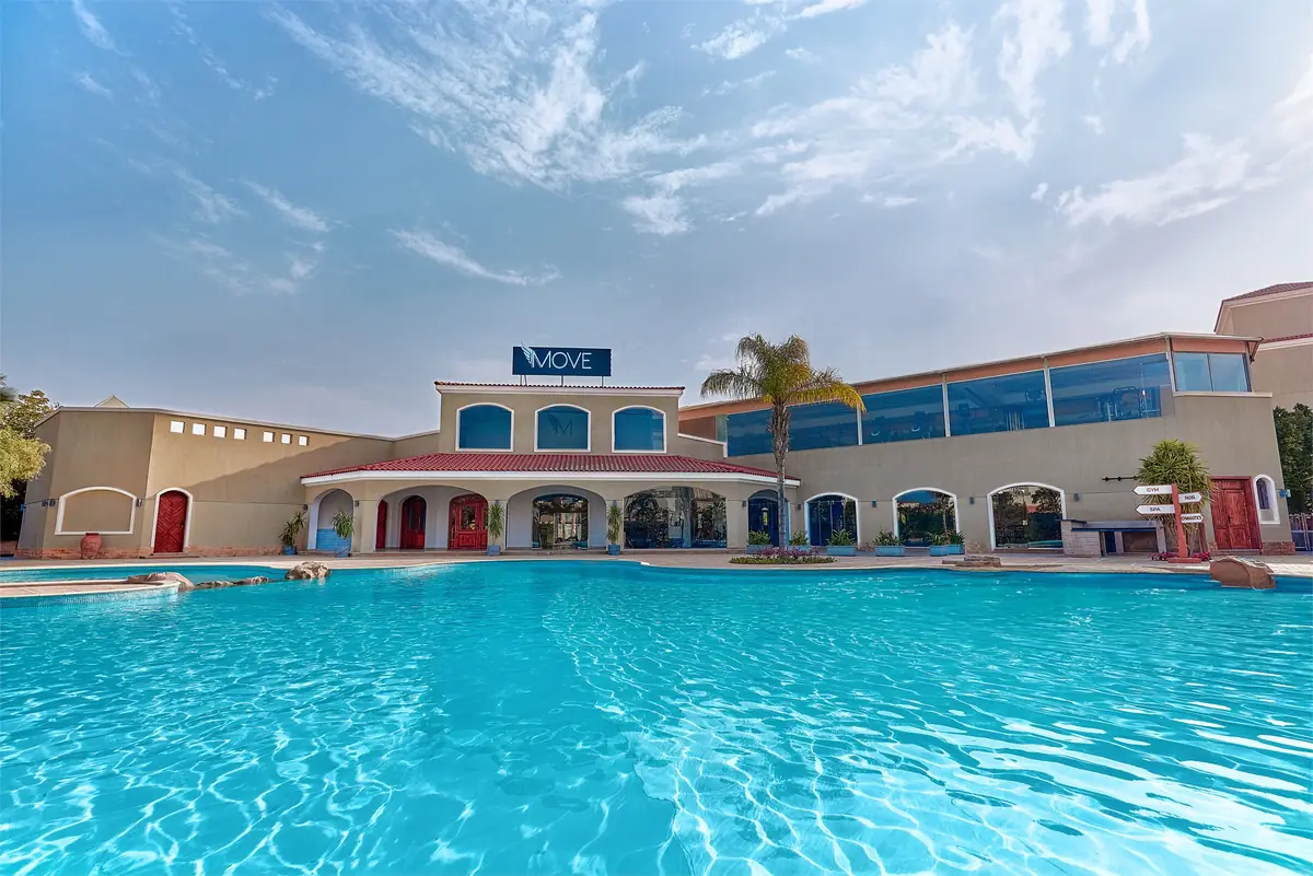 Move – Green Heights Sports Complex – Large pool in front of the arched, tile-roofed clubhouse under a blue sky