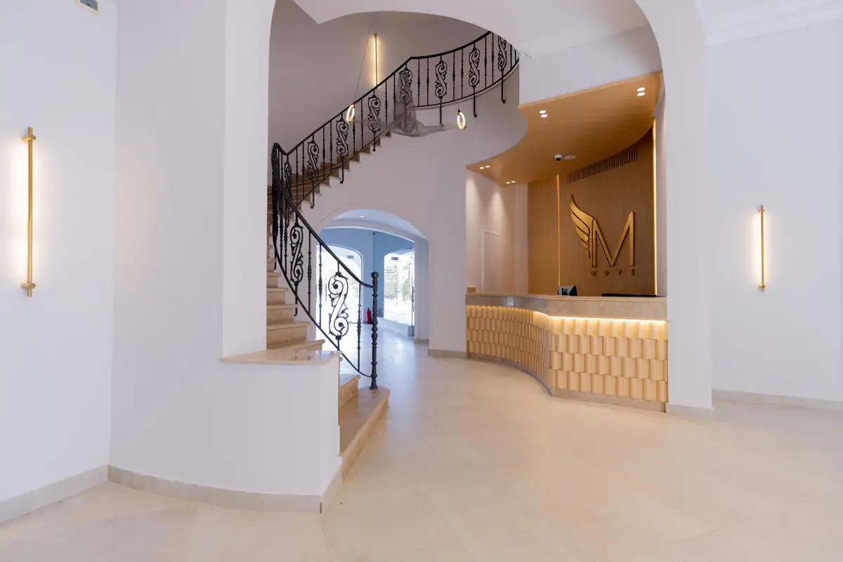 Move – Green Heights Sports Complex – Reception with a curved timber desk below a wrought-iron spiral staircase