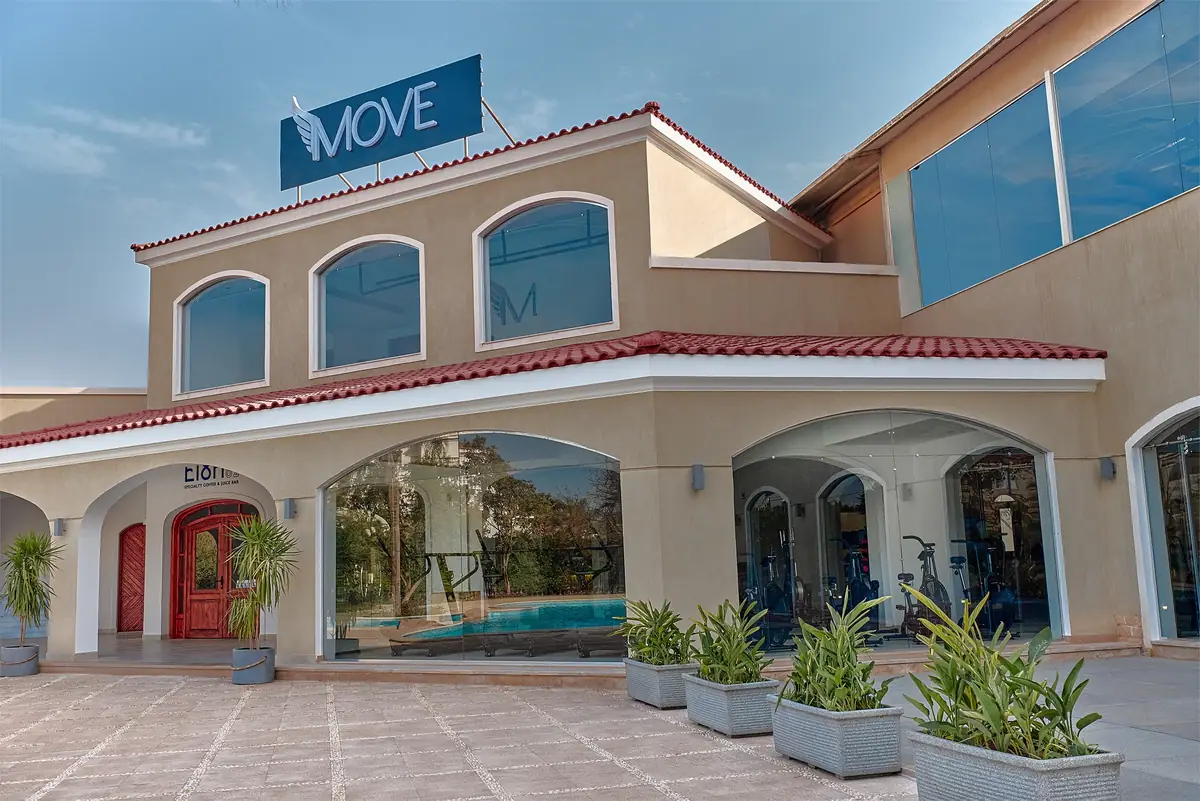 Move – Green Heights Sports Complex – Arched clubhouse façade with a glass-walled upper floor and planters