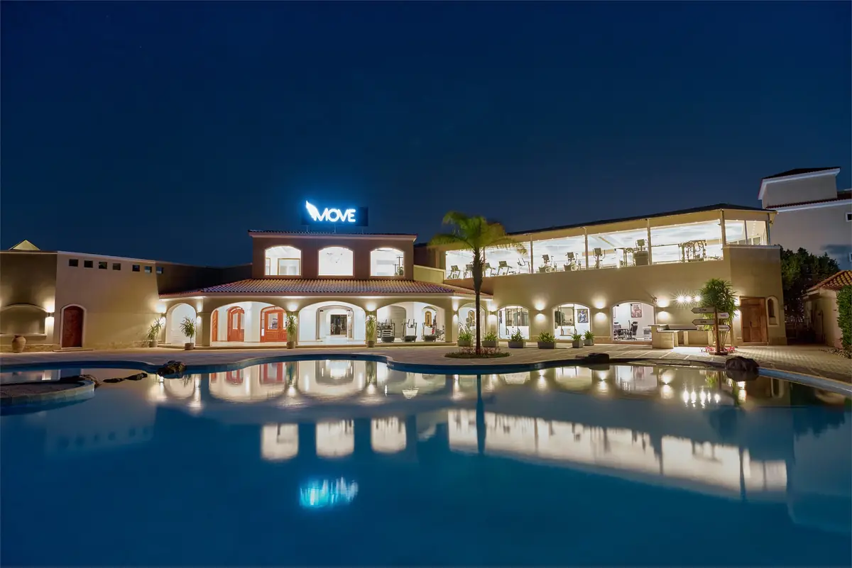 Move – Green Heights Sports Complex – Night view of the lit clubhouse reflected in the pool