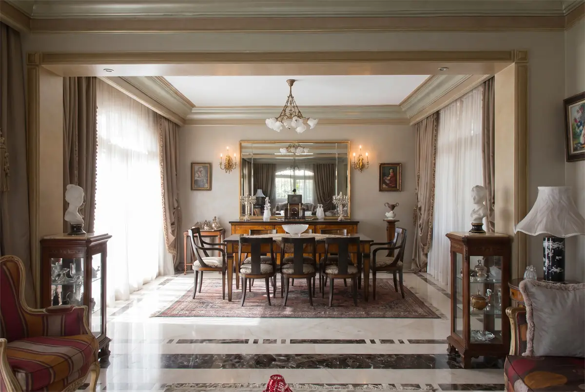 Mrs. M.A.'s Villa – غرفة طعام رسمية خلف فتحة بزخارف جبسية مع ثريا وأرضية حجرية مطعمة