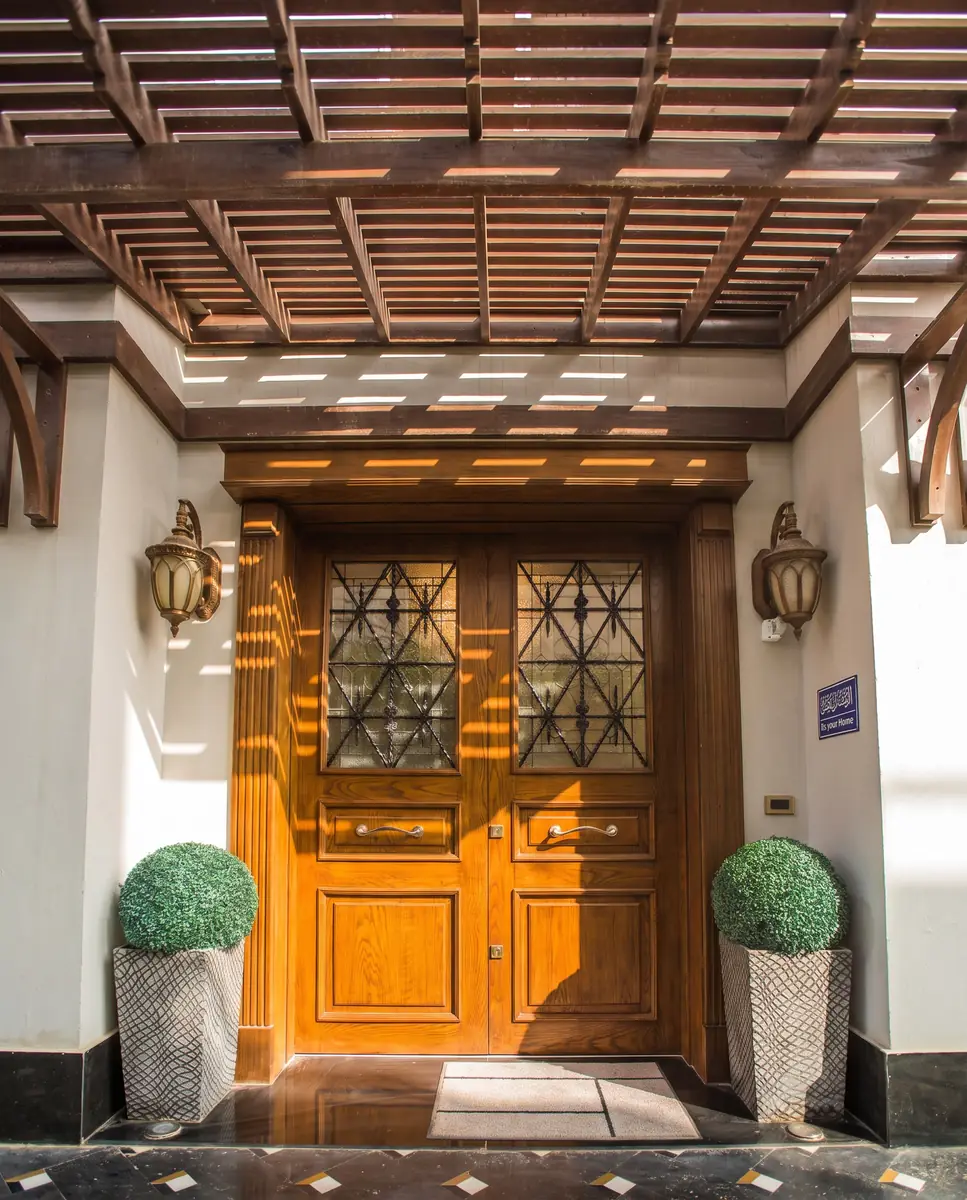 Mrs. M.A.'s Villa – باب خشبي منحوت مزدوج تحت برجولا شرائحية تحيط به فوانيس ونباتات مشذبة