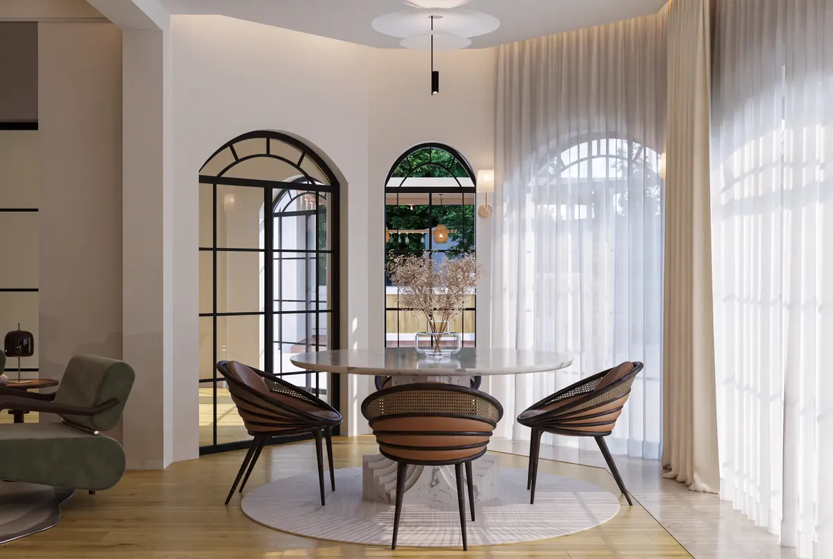 Mrs. S.T.'s Villa – V.24 – طاولة طعام دائرية بكراسٍ منحنية أمام نوافذ مقوسة بإطارات فولاذية وستائر شفافة