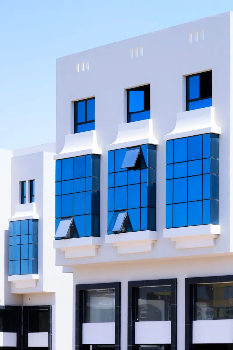 Prima Vista – Medical Office & Commercial Mall – واجهة بيضاء ناصعة بنوافذ بارزة من الزجاج الأزرق الزاهي وفتحات تهوية علوية