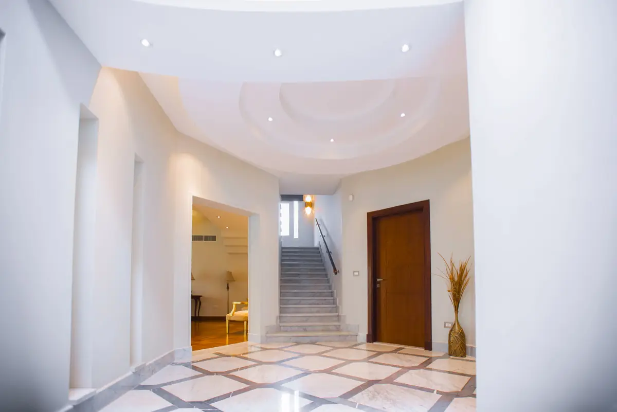 Prof. Dr. H.F.'s Villa – بهو مدخل منحنٍ بأرضية رخامية بنقش هندسي ودرج