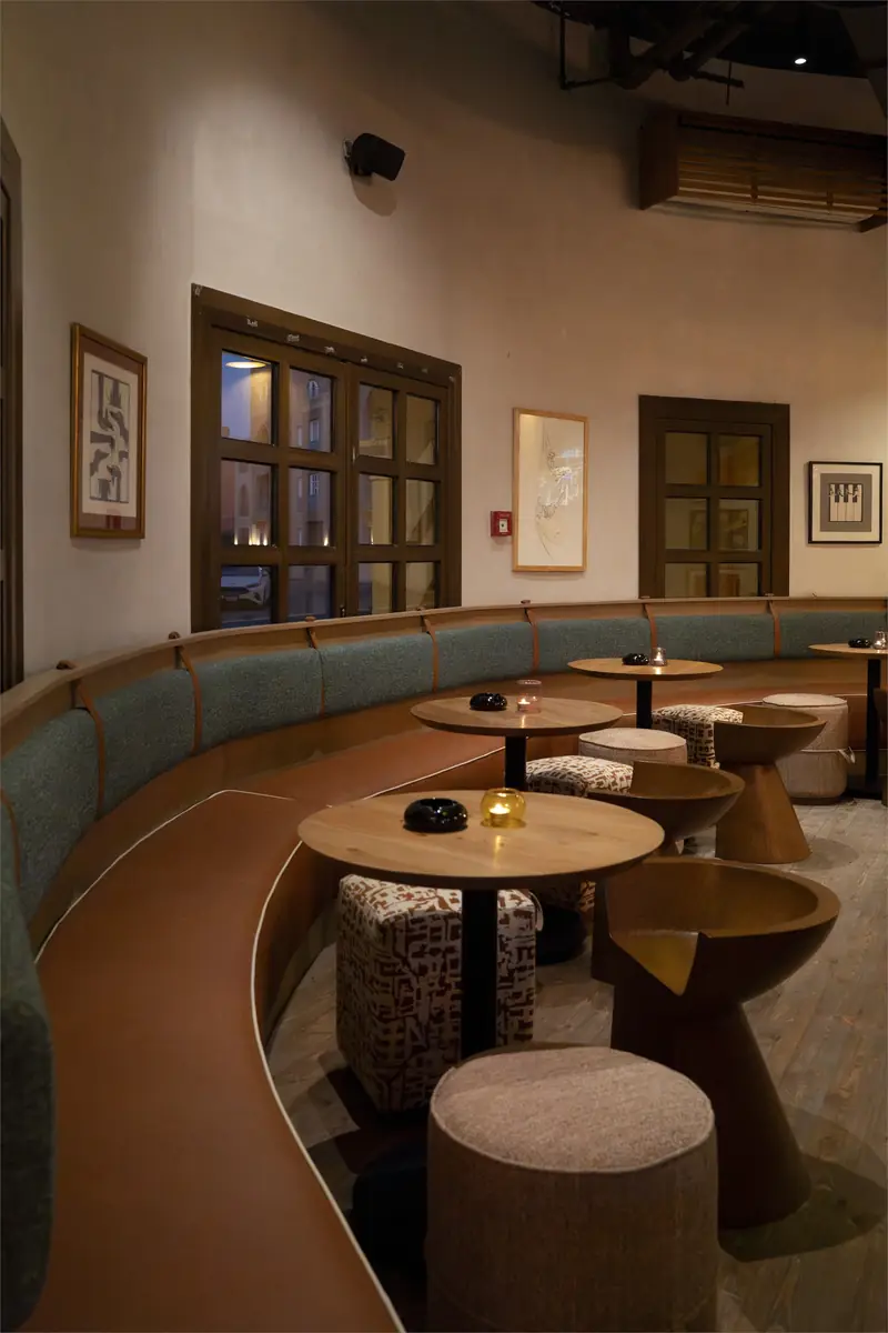 Rush – Sports Bar – مقعد منحنٍ أخضر مع طاولات خشبية مستديرة ومقاعد منخفضة منقوشة ولوحات مؤطرة